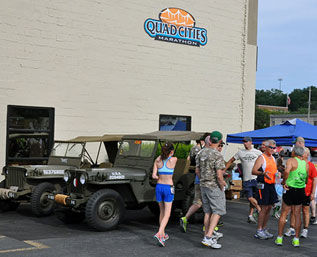 Photo of runners next to military jeeps